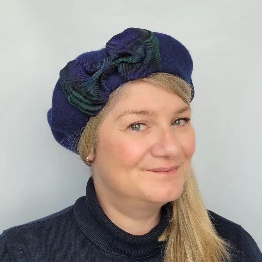 Navy Blue Beret with a Blackwatch Tartan Bow worn by a white woman in her 40s with long blonde hair